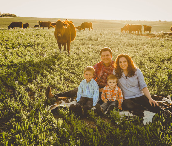 David & Amy Bachman with their sons, Edmond & Isaac. Behind them is their cow herd.